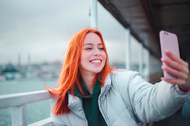 Atractiva joven pelirroja tomando una foto selfie en un ferry