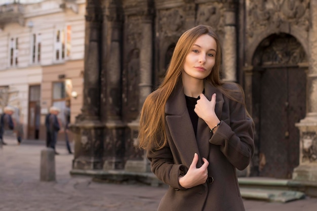 Atractiva joven rubia con un abrigo gris en la calle