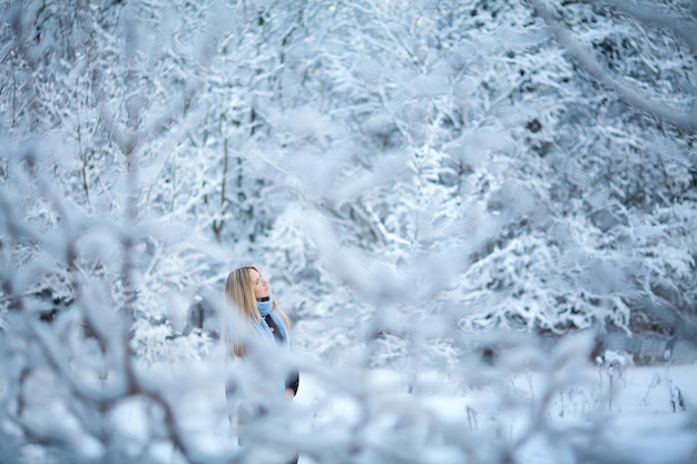 Atractiva joven rubia caminando en el bosque de invierno