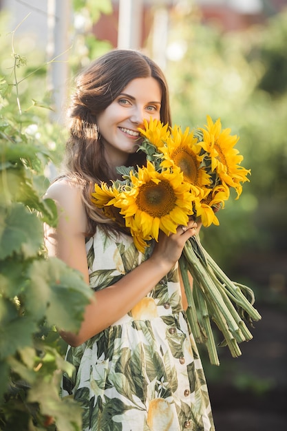 Atractiva joven rubia con ramo de girasoles. Concepto libre de alergias. Hembra con flores en verano.