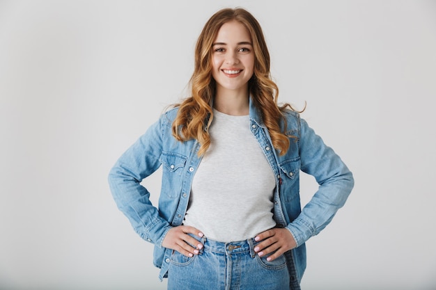 Atractiva joven vistiendo ropa casual que se encuentran aisladas sobre blanco, con las manos en las caderas