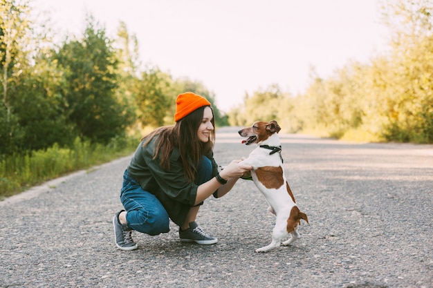 Atractiva jovencita jugando con su perro mientras camina al aire libre