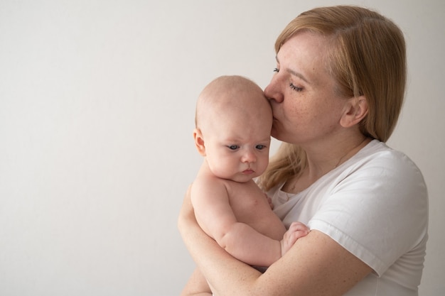 Atractiva madre feliz abrazo beso al pequeño bebé. Familia feliz. Amor sin fin. En casa. Amor. Dulce. Sensibilidad.