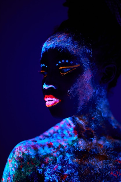 Atractiva modelo femenina joven en bodyart de luz negra brillante,  encantadora mujer tranquila en atención, pacífica, de pie mirando al  costado, posando a la cámara. arte corporal, fantástico, fluorescente,  luminiscencia