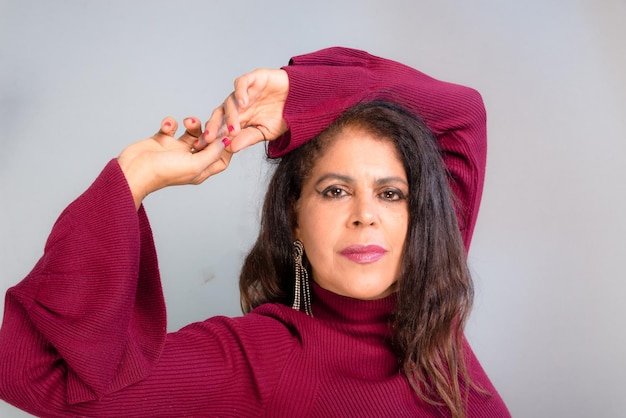 Foto atractiva morena vestida con traje rojo sonriendo y confiada foto de estudio aislada sobre fondo gris