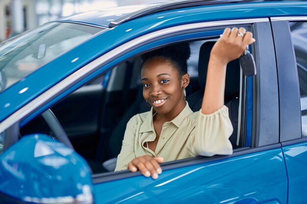 Atractiva mujer afro joven disfruta de ser propietario de un auto nuevo