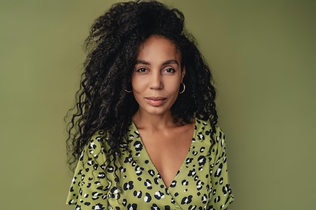 Atractiva mujer afroamericana negra posando en un elegante vestido estampado de leopardo verde aislado en el fondo del estudio verde tendencia de la moda de verano cabello rizado sonriente feliz