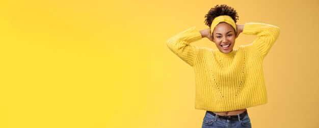 Atractiva mujer afroamericana optimista y afortunada divirtiéndose recostarse con las manos detrás de la cabeza sonriendo riendo