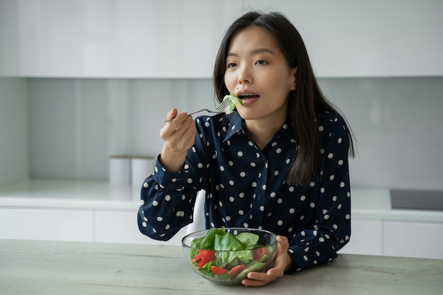 Atractiva mujer asiática come una ensalada de verduras frescas el concepto de dieta y alimentación saludable