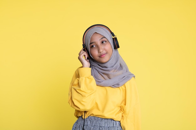 Atractiva mujer asiática escuchando música con fondo amarillo Disfrutando de la música