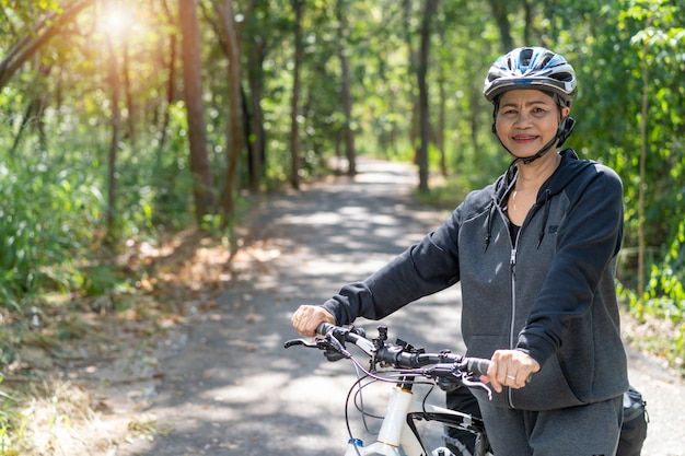 Atractiva mujer asiática senior con bicicleta en el parque