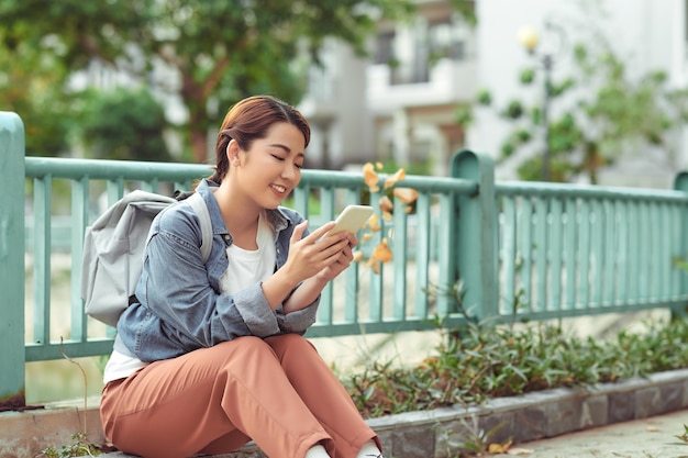 Atractiva mujer asiática con teléfono inteligente en el parque