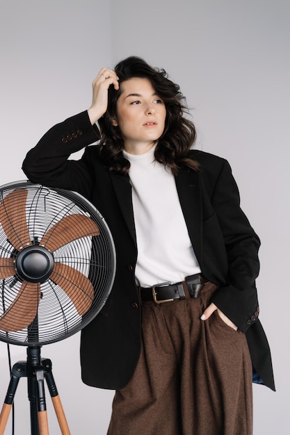 Atractiva mujer con aspecto de negocios. Modelo morena con camisa blanca, chaqueta de hombre negra y pantalones holgados marrones. Invierno otoño otoño o primavera atuendo mínimo.