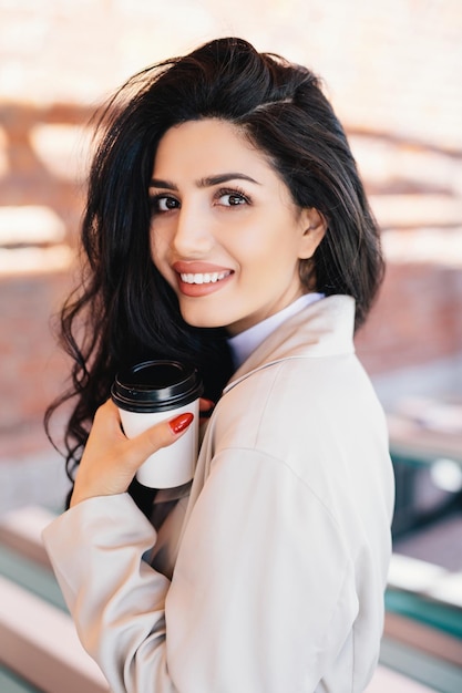 Atractiva mujer bebiendo té al aire libre disfrutando de un descanso para tomar café Estilo de vida tranquilo con ojos cálidos cabello oscuro