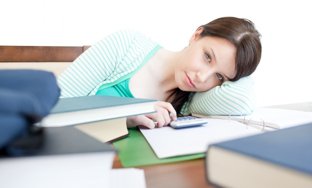 Atractiva mujer cansada estudiando en una mesa