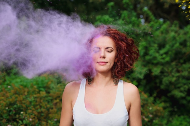 Atractiva mujer caucásica con cabello ondulado jugando con pintura seca de colores en el Festival de Holi