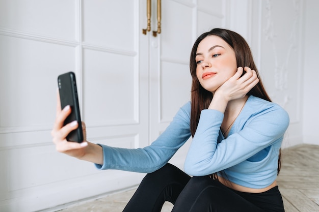 Atractiva mujer caucásica mediante teléfono móvil después del entrenamiento físico en casa.