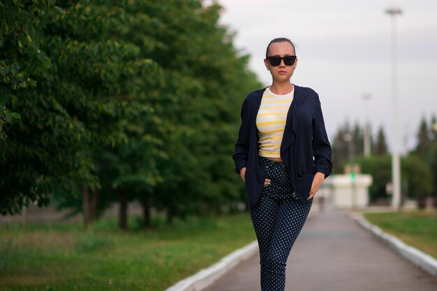 Atractiva mujer delgada y tranquila con camisa a rayas amarillas y blancas y azul con pantalones de lunares blancos