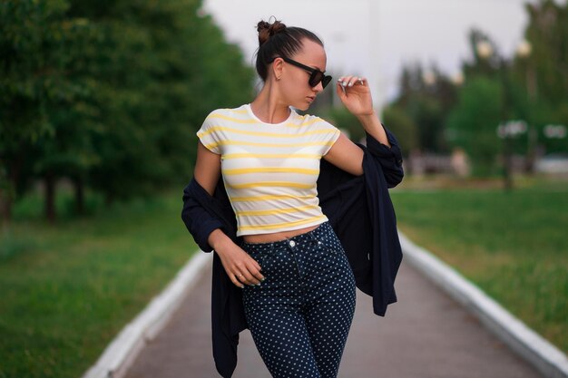 Atractiva mujer delgada y tranquila con camisa a rayas amarillas y blancas y azul con pantalones de lunares blancos