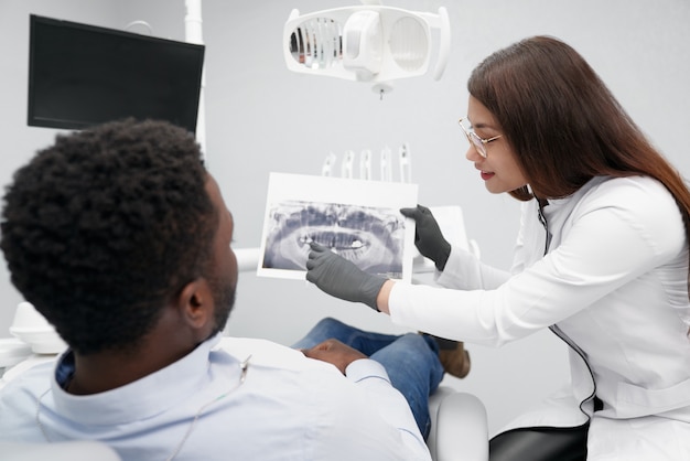 Atractiva mujer dentista manteniendo la imagen de rayos x de los dientes