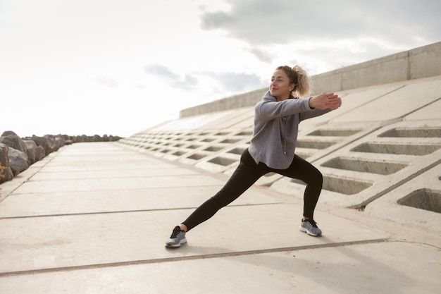 Atractiva mujer deportiva en ropa deportiva entrena al aire libre Calentar o estirar un estilo de vida saludable