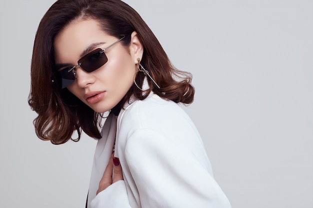 Atractiva mujer elegante con cabello oscuro en traje blanco de moda