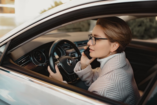 Atractiva mujer elegante sentada en el auto vestida con abrigo