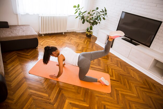 Atractiva mujer haciendo ejercicio en su sala de estar