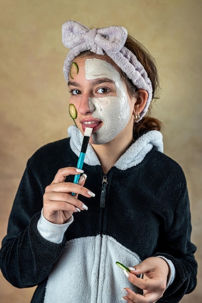 Atractiva mujer hermosa aplicando mascarilla blanca de arcilla facial con cepillo Procedimiento de cuidado de la piel de aromaterapia Spa