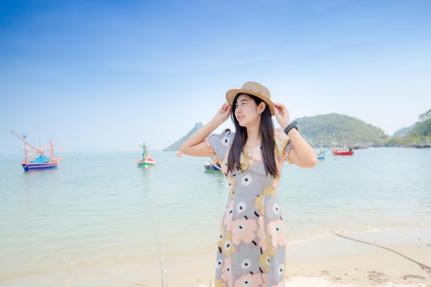 Atractiva mujer joven asiática con vestido blanco sonrisa disfrutar con las vacaciones de verano en la playa feeli