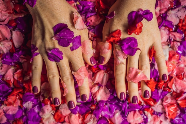 Atractiva mujer joven en el baño con pétalos de flores tropicales y tratamientos de spa con aceites aromáticos para