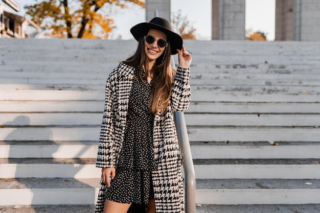 Atractiva mujer joven caminando en otoño con abrigo