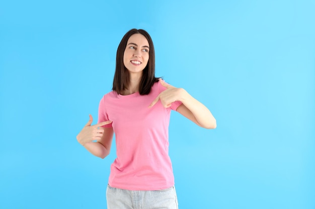 Atractiva mujer joven en camiseta sobre fondo azul.