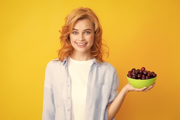 Atractiva mujer joven comiendo cereza fresca Frutas saludables de verano Fondo amarillo Hermosa mujer posando con una niña de cereza con promoción de cereza