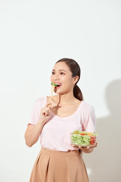 Atractiva mujer joven comiendo ensalada