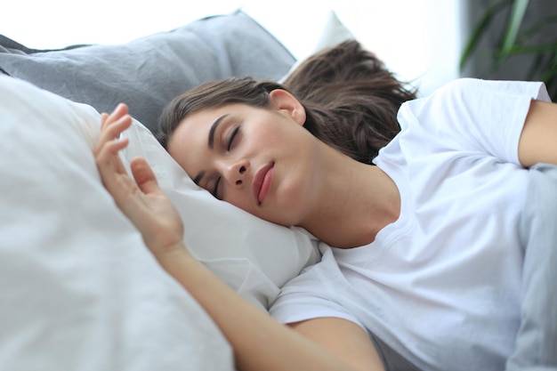 Atractiva mujer joven durmiendo en la cama en casa