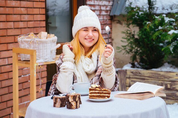 Atractiva mujer joven feliz sentada y comiendo postre en la cafetería