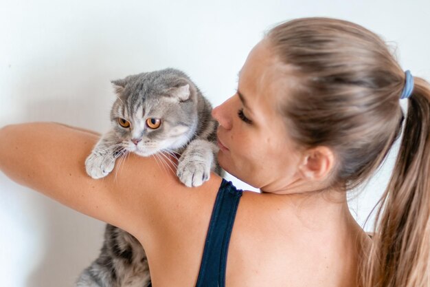 Atractiva mujer joven con pelo largo abrazando a su mascota con sonrisa interior retrato de mujer linda