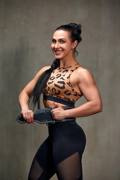 Atractiva mujer joven de pie fuerte en el gimnasio y flexionando los músculos hermoso modelo de fitness atlético posando después de los ejercicios