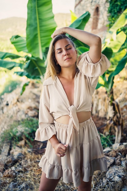 Atractiva mujer joven de piel clara se encuentra cerca de árboles de plátano en el parque tropical