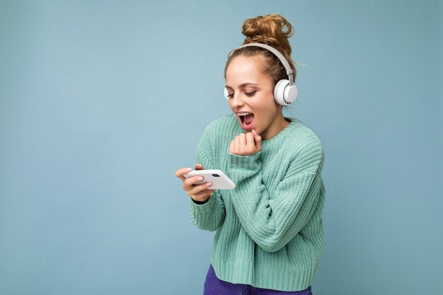 Atractiva mujer joven positiva emocional vistiendo suéter azul aislado