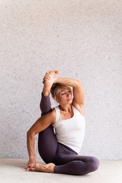 Atractiva mujer joven practicando yoga mientras usa ropa deportiva en el interior