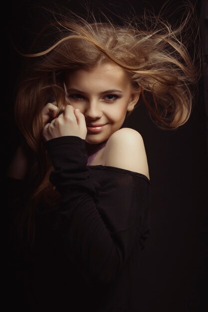Atractiva mujer joven con purpurina en el cuello y viento que sopla su cabello