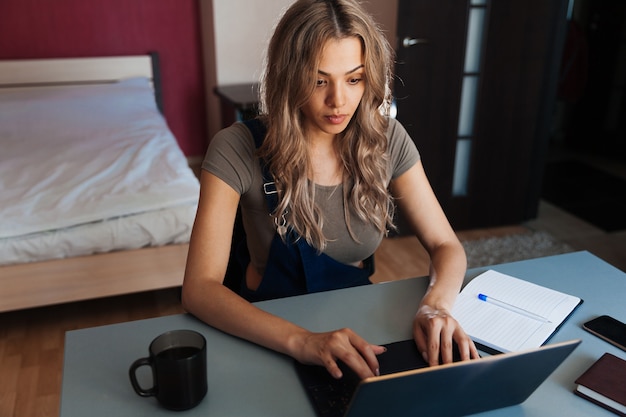 Atractiva mujer joven que trabaja en casa usando la computadora portátil