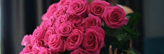 Atractiva mujer joven con ramo de flores rosas en cumpleaños o aniversario