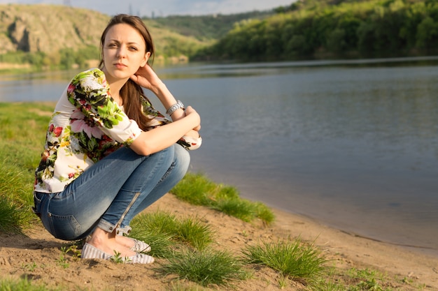 Atractiva mujer joven sentada junto a un lago