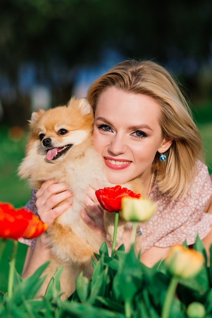 Atractiva mujer joven sosteniendo perro spitz fuera