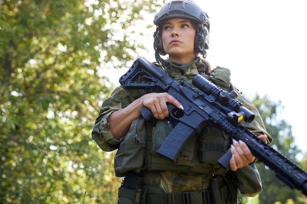 Atractiva mujer militar valiente con una pistola en el bosque, supervivencia en el bosque salvaje