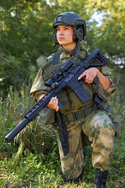 Atractiva mujer militar valiente con una pistola en el bosque, supervivencia en el bosque salvaje