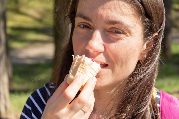 Atractiva mujer morena afuera en un día soleado divirtiéndose y comiendo helado